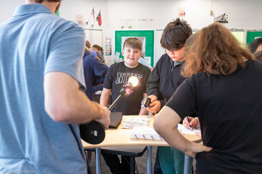 A student smiles while looking at a lightbulb during the presentation.