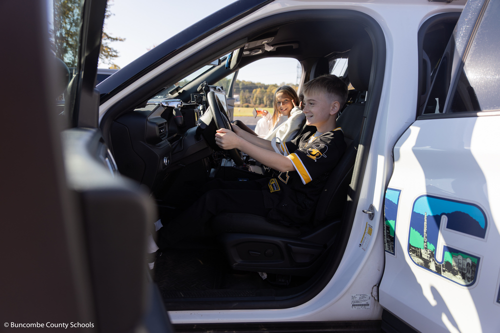 Male student sitting in the driver seat of an Asheville Police car.