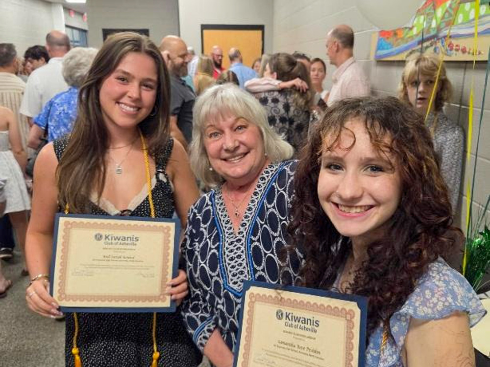 Rell Bound and Sam Peshkin stand with a representative of the Kiwanis Club between them. Both students are holding certificates.