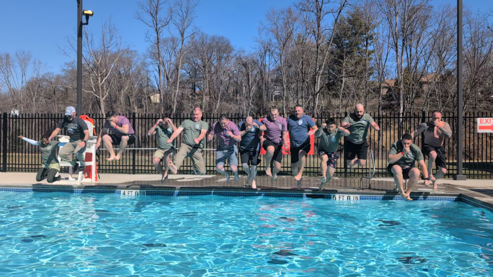 A line of School Resource Officers jumps into the pool.