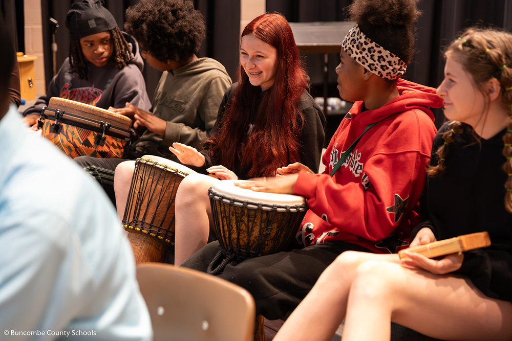 Group of students playing on a variety of African drums.