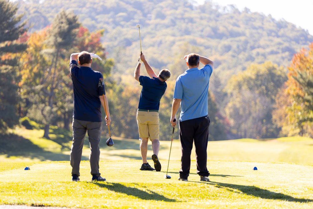 Two men watching one man tee off