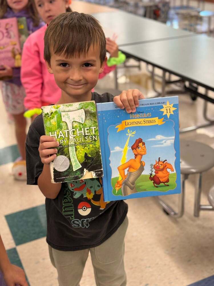 Little boy holding up two books. 