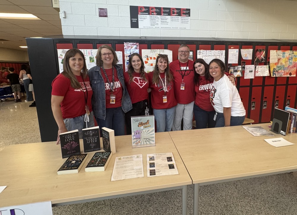 Teachers wearing red Erwin High shirts pose for a photo in front of red lockers.