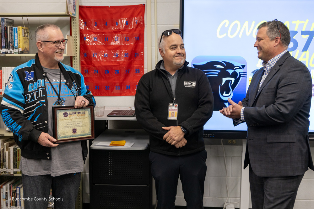 Mr. Roberts stands next to Mr. Stowe and Mr. Cody. He is holding a plaque for his years of service.