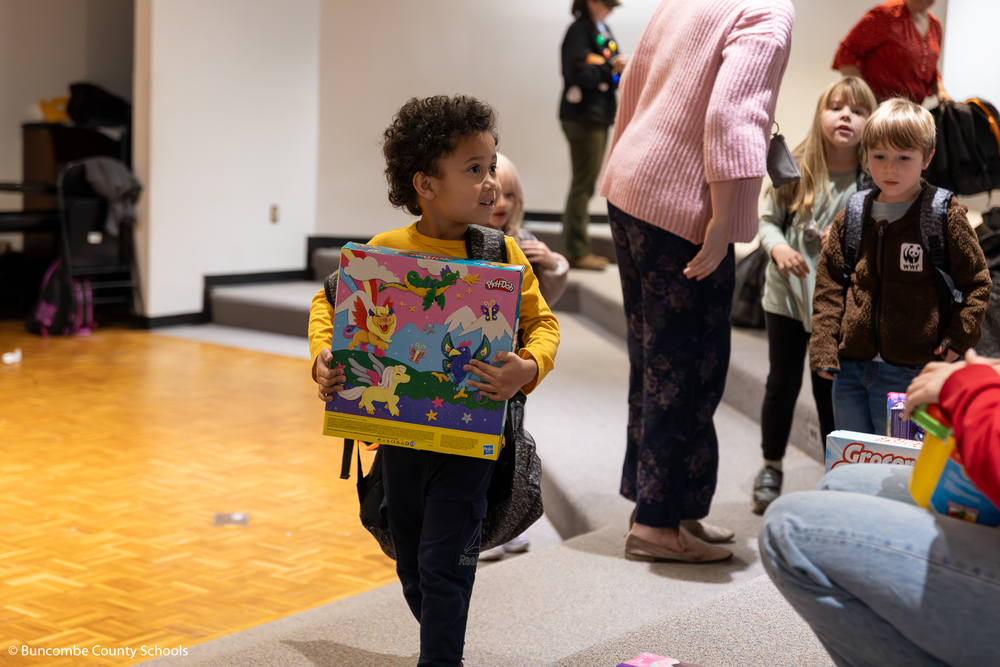 Kindergarten boy carrying a big box of play-doh.