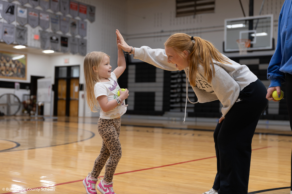 High school student giving a preschooler a high five. 