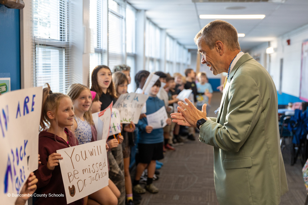 Students with congratulatory signs line the hallway as Dr. Jackson stands before them clapping.