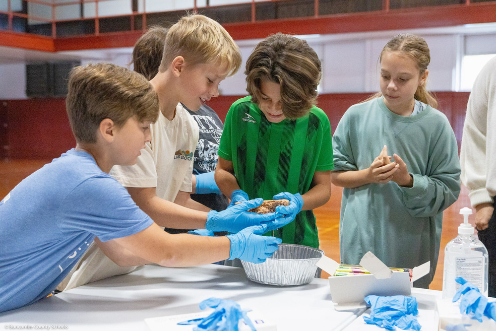 Four kids wearing gloves handle a human brain.
