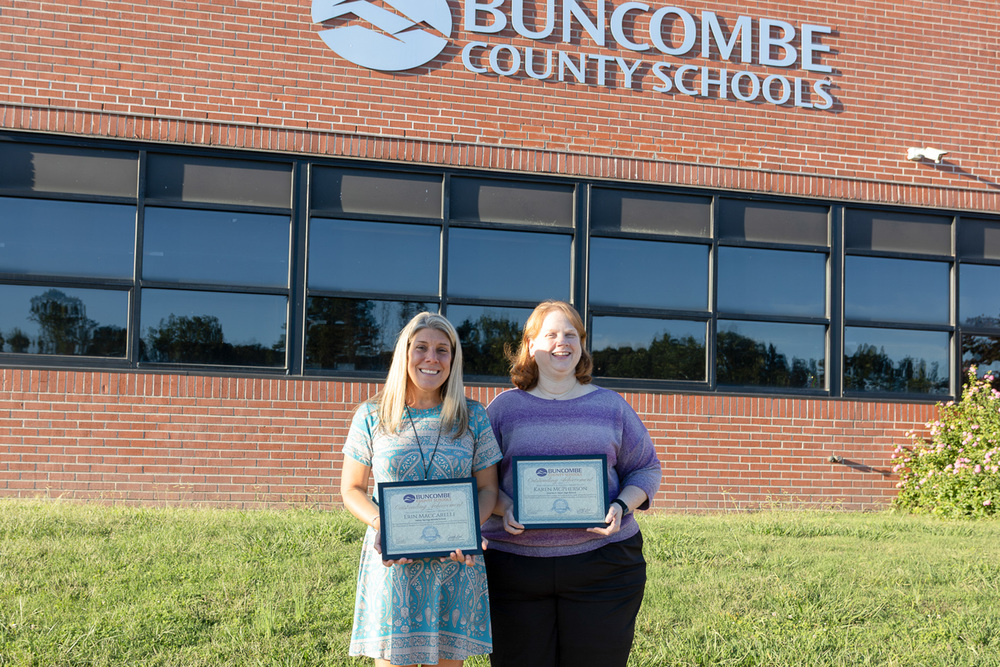 Ms. Macarelli and Ms. McPherson pose for a photo outside of BCS Central Services. They are each holding a framed certificate.