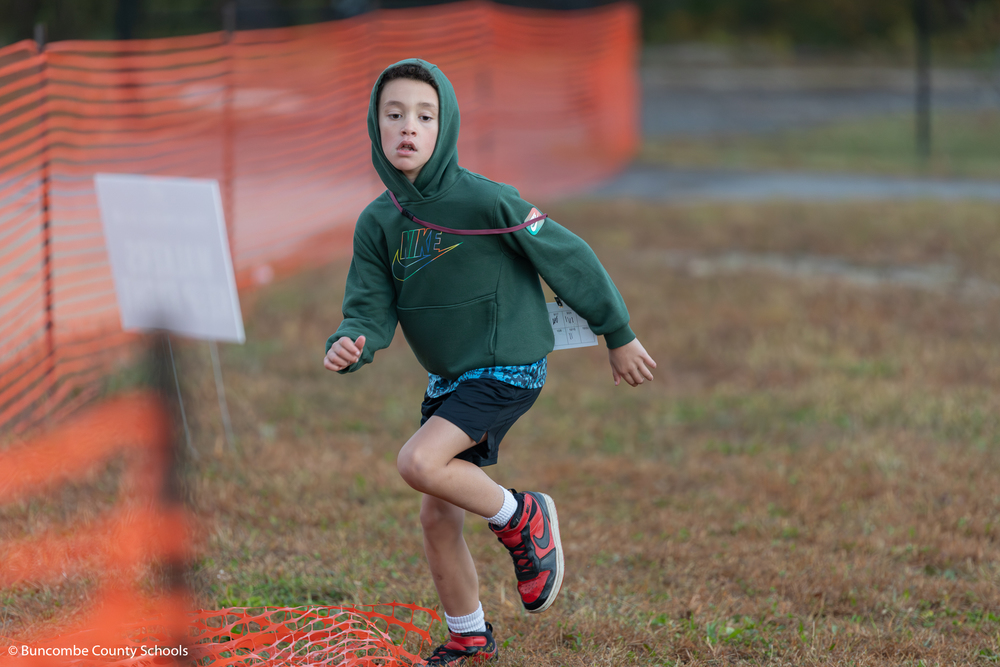 Boy in green hoodie and black shorts running.