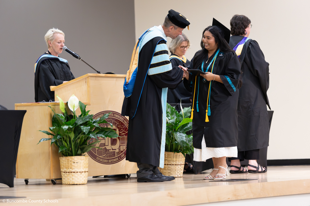 Dr. Jackson shakes the hand of a student in a cap and gown who is holding a diploma.
