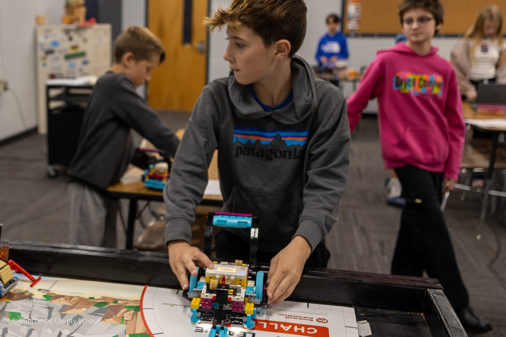 A student  works at building a LEGO robot at the table