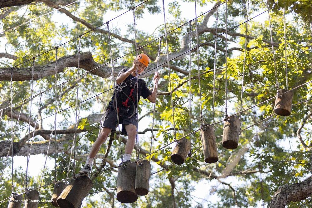 Student scales ropes course at AVL Adventure Center