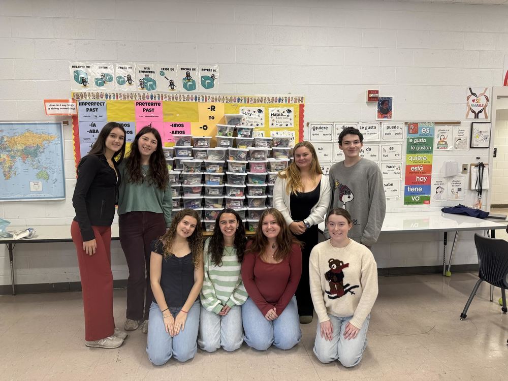 Group of students gathered around the boxes they helped to assemble.