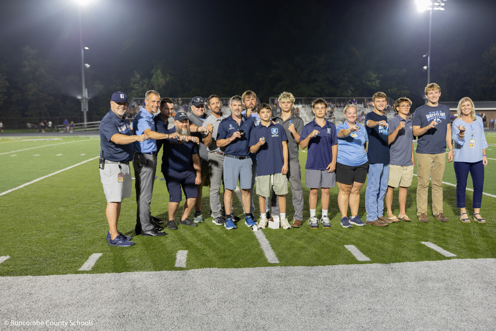 The wrestling team, coaches, and principals showing off the new state championship rings. 