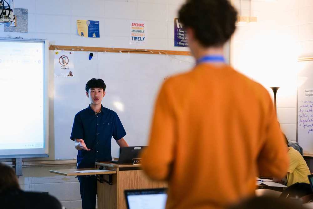 Two students face each other in a classroom having a debate.