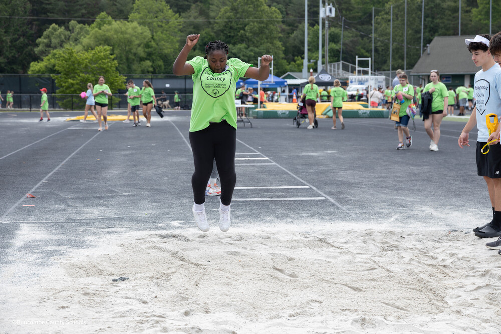 Student jumping into a sand pit to see how far she can jump. 