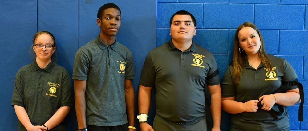 4 ROTC members against a blue wall