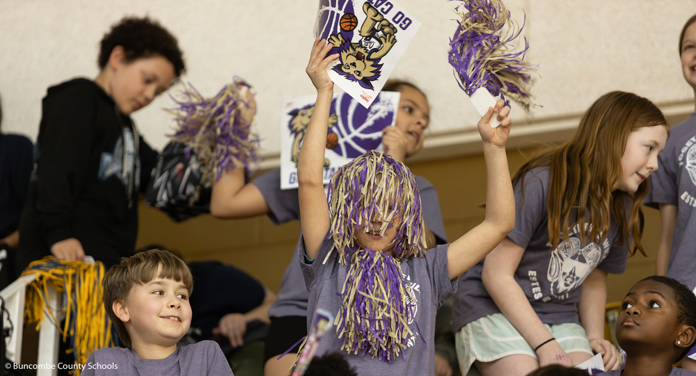 Student cheering on the teams with pom poms. 