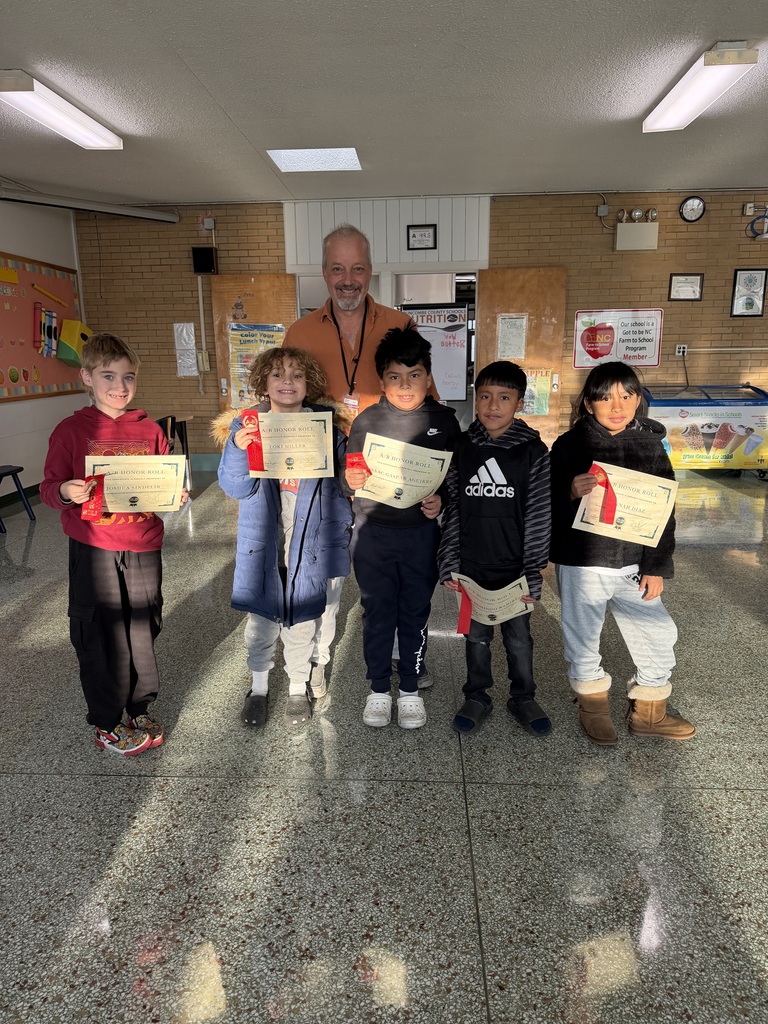 Five third grade students stand in front of their teacher holding their A/B honor roll certificates. 