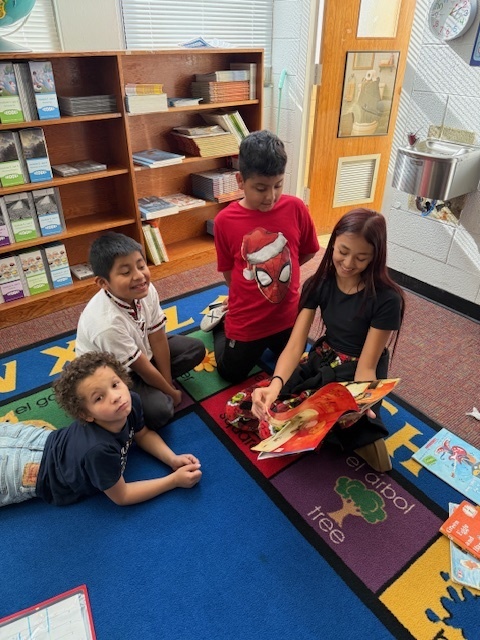 Middle school student reads to three secondgrade students.