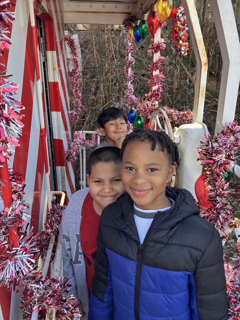 Three students stand smiling on a railcar.