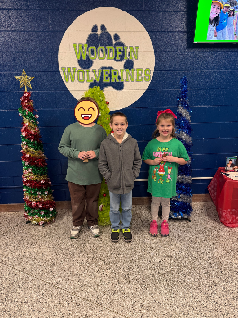 Our top 3 gingerbread friend decorators stand in front of the Woodfin Elementary sign smiling. 