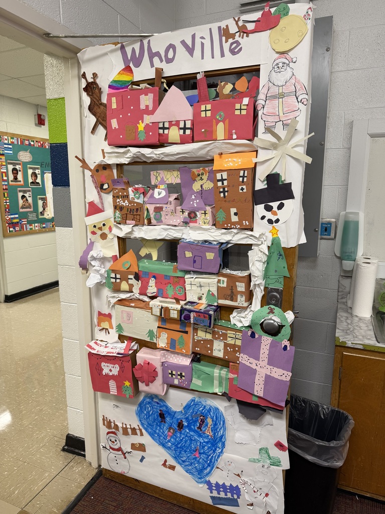 A door with the word "Whoville" at the top. Many different colored houses made of construction paper displayed. Ornament, snowman, and present decorations around the perimeter. 