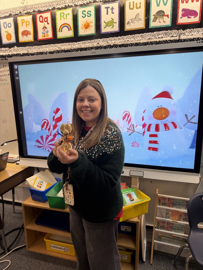 Teacher standing with puppy in front of snowman display. 