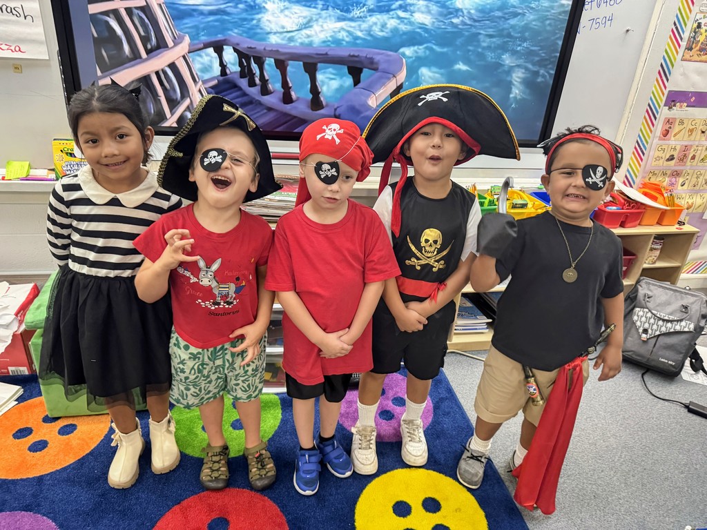 Kindergarten students standing in front of smartboard smiling.
