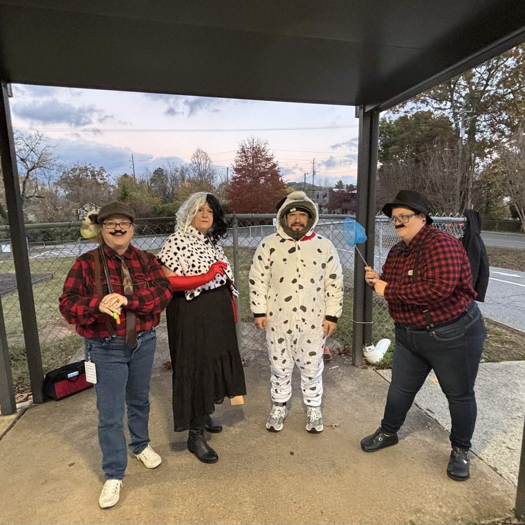 Staff dressed for Halloween as Cruella Deville, a dalmatian, and two henchmen. 