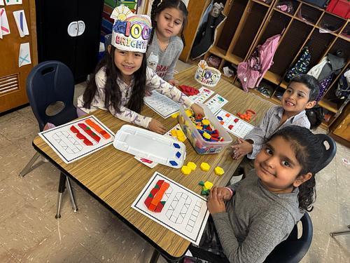Students smiling with 100 on their desk.
