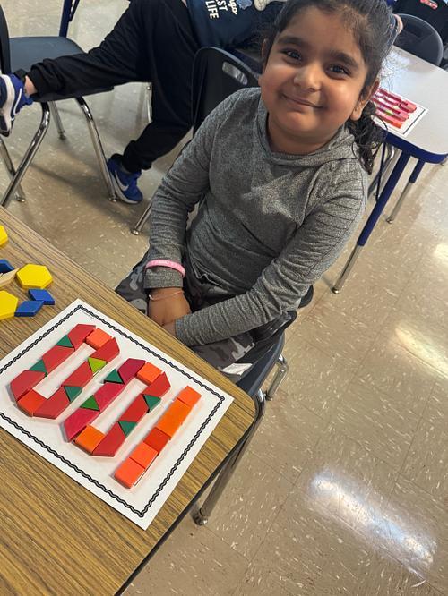 Student smiling with 100 on her desk.