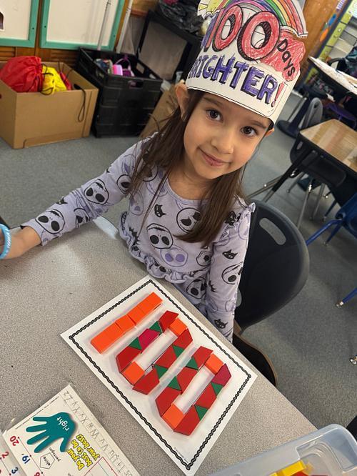 Student smiling with 100 on her desk.