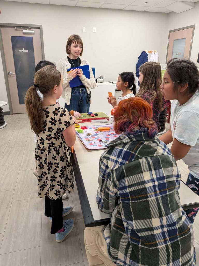 Students stand around game table with their board game.