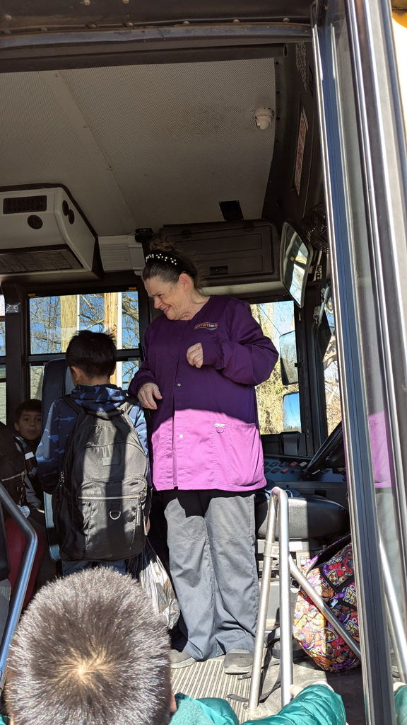Bus driver helps students on bus.