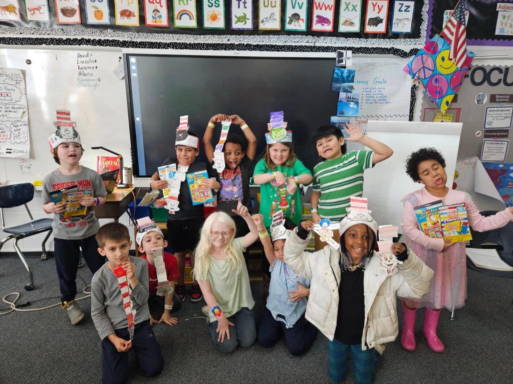 Students stand in front of classroom in Cat in the Hat paper hats. 