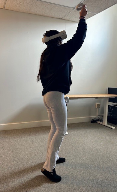 student with a VR headset reaching toward the ceiling