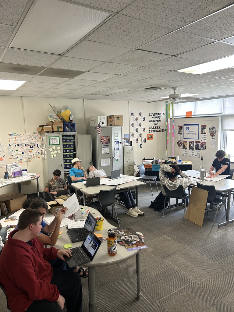 students at tables working on computers to create a project 