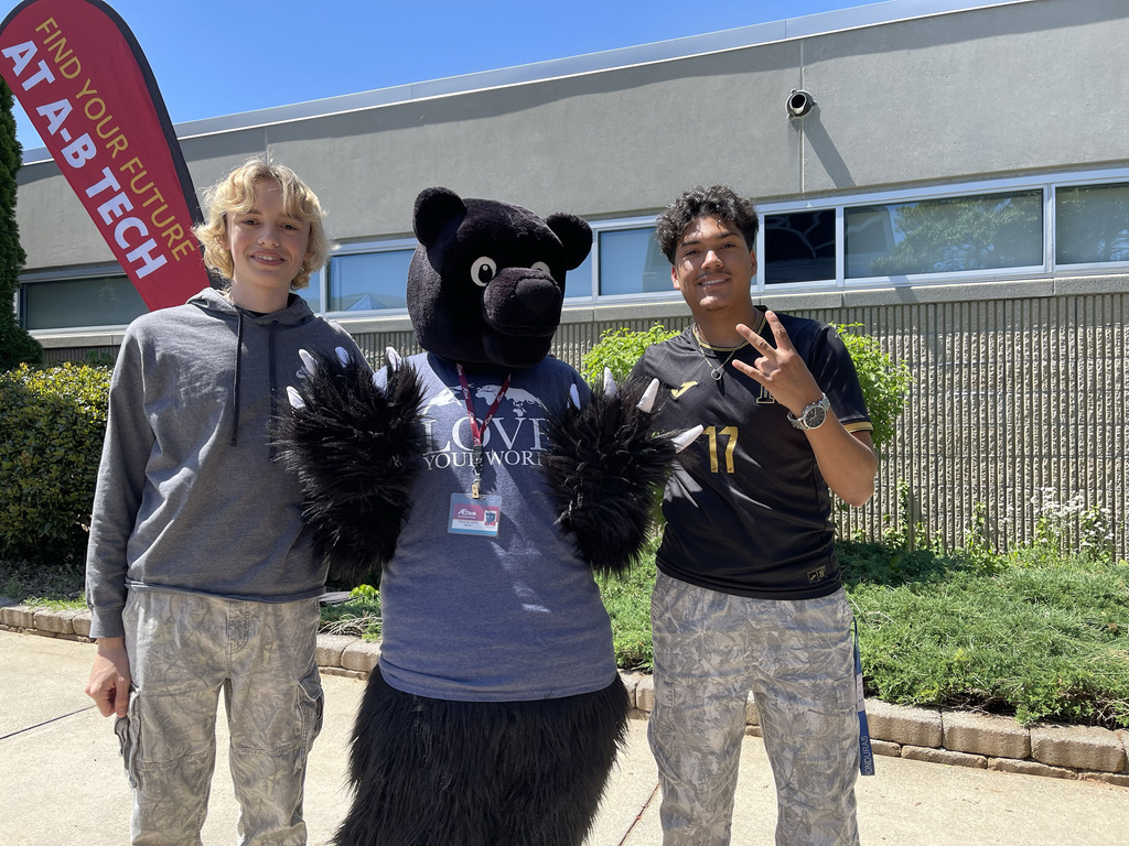 two students standing next to the AB Tech bear mascot 
