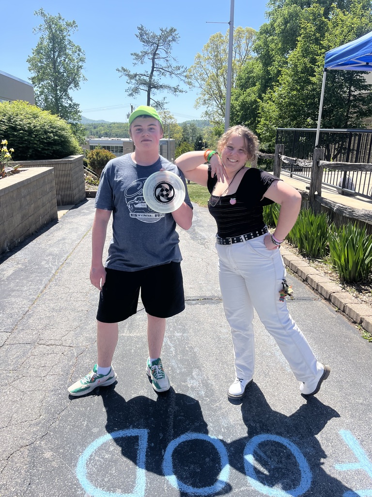 two students standing outside holding a frisbee