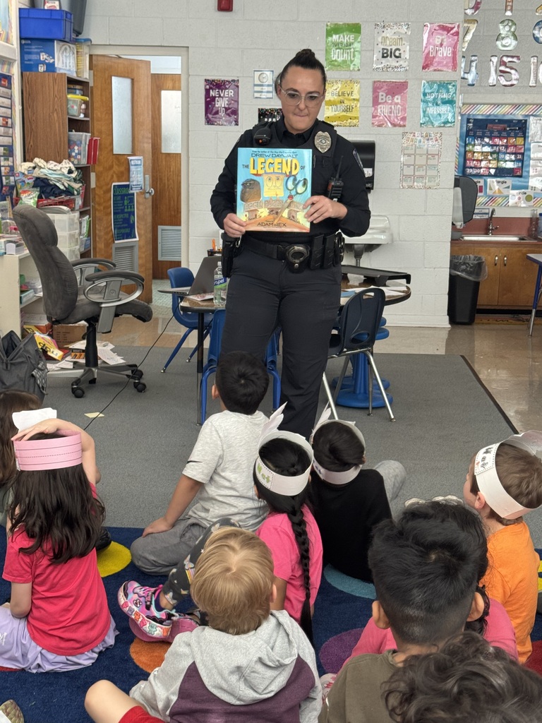 Officer holds picture book up in front of a group of students. 