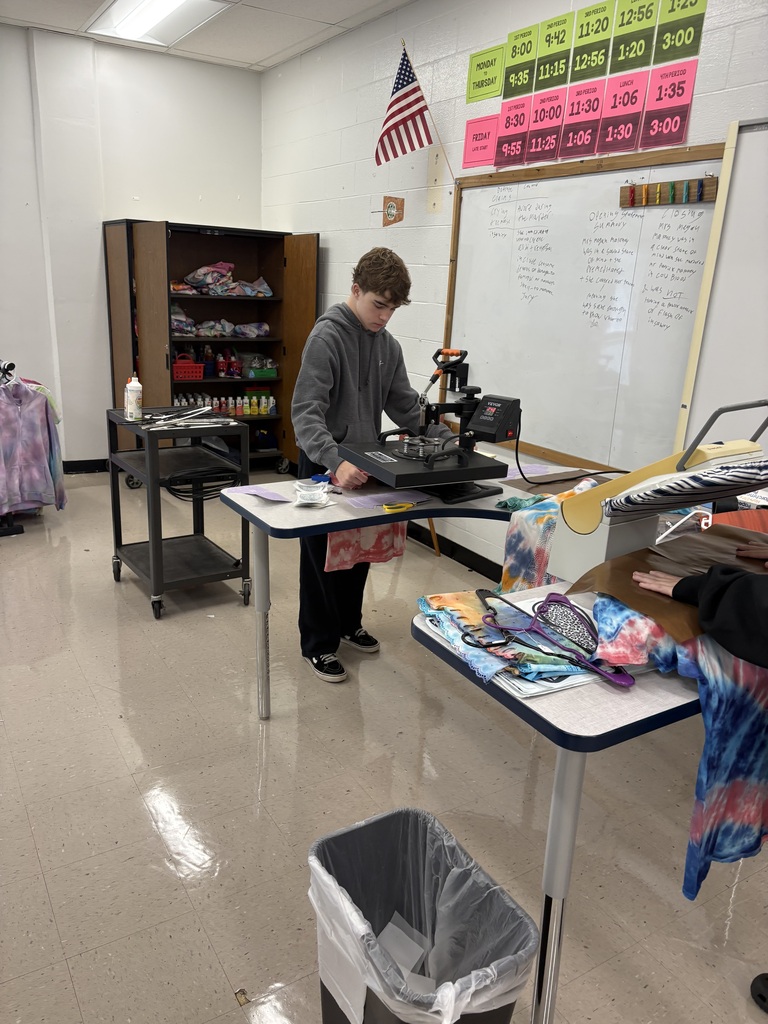 Students using a t shirt press to finish shirts. 