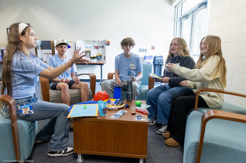 Five students play an ice breaker game that involves throwing a ball and answering questions.