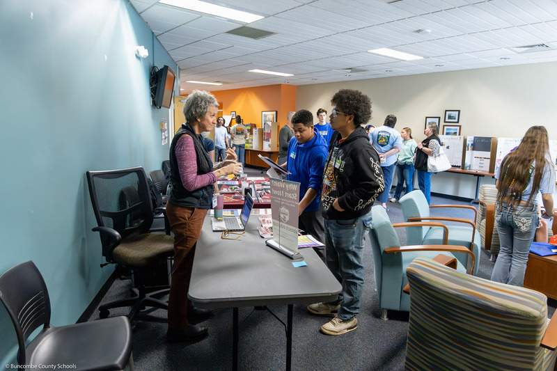 An adult speaks to two eighth graders about her organization.