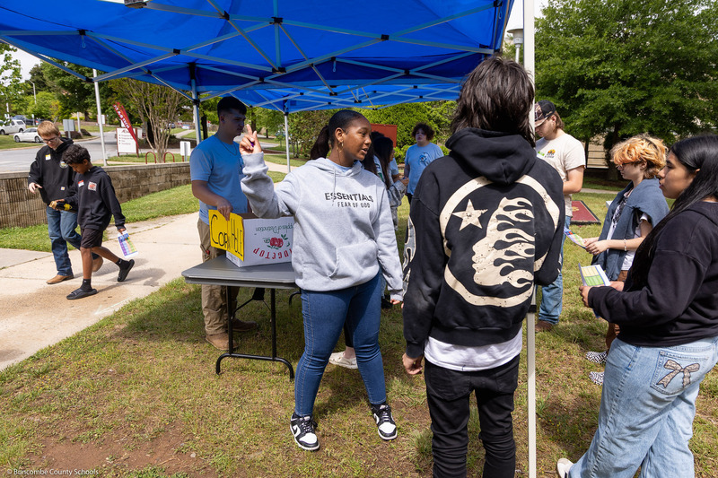 A BCCI student speaks to potential students outside under a canopy.