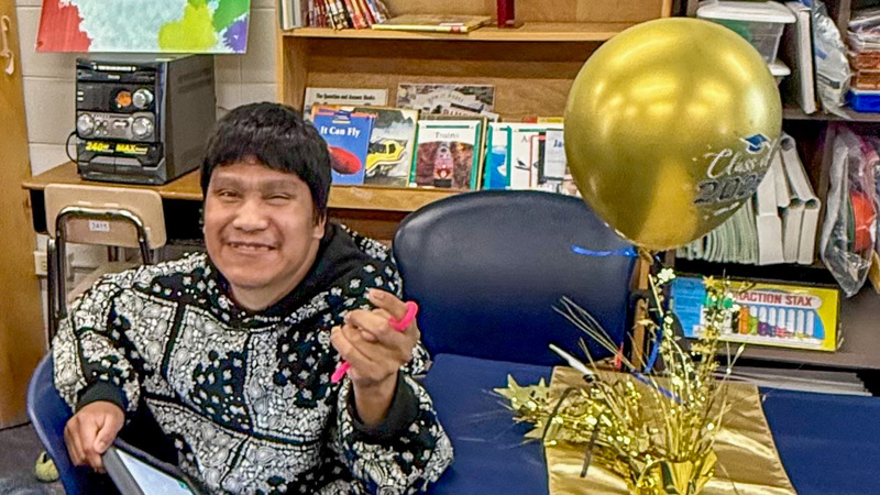 A PEP students smiles next to a balloon.