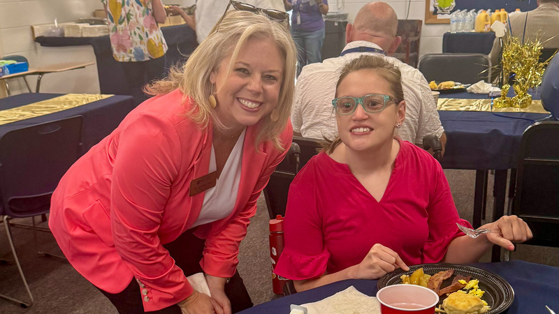Dr. Reed smiles next to a PEP student. Both are wearing red.