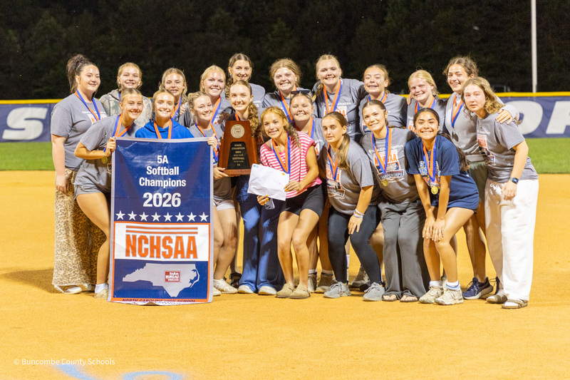 Enka players pose on the field holding the banner and trophy